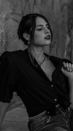 Monochrome portrait capturing a stylish woman in elegant attire against a textured background.