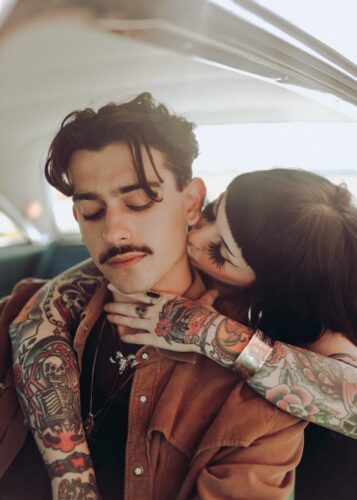 A tattooed couple shares an affectionate moment inside a vintage car, Des Moines.