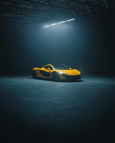A captivating shot of a sleek yellow sports car illuminated in a dimly lit industrial warehouse.