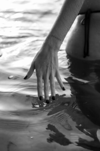 Elegant black and white photo of a woman's hand in water, captured naturally.
