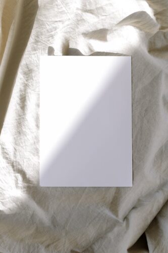 Blank card placed on crumpled fabric with sunlight, perfect for mockups and designs.