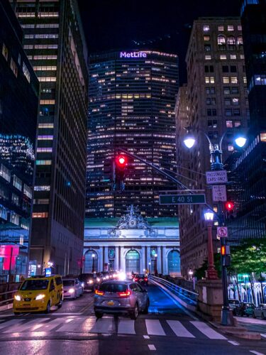 Night view of New York City traffic near Grand Central Terminal, with MetLife Building in the background.