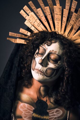 A woman adorned as a Catrina with detailed Día de Muertos makeup and cultural attire.