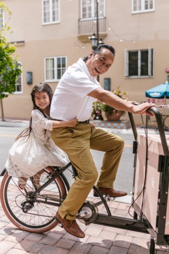 Smiling father and daughter on bicycle enjoying a sunny day outdoors in the city.