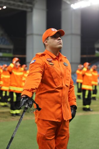 Group of firefighters in orange uniforms during a formal ceremony at night.