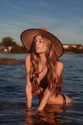 Beautiful woman in swimwear posing outdoors in tranquil water scene.