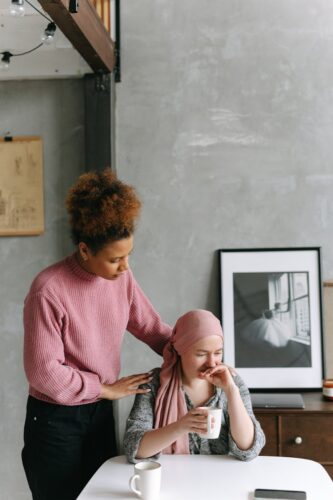Two women sharing a comforting moment indoors, highlighting support and friendship.