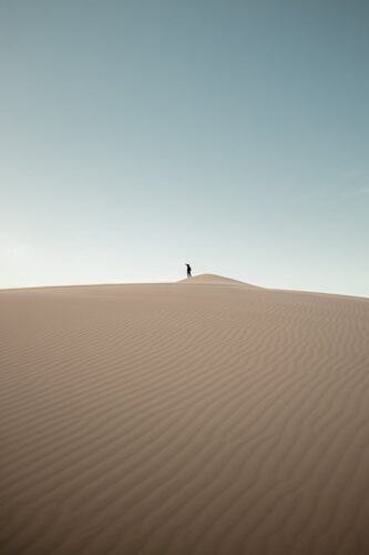 A solitary figure atop the Samalayuca dunes under a vast desert sky.