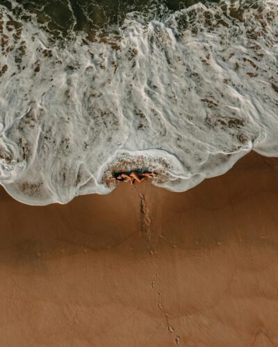 Aerial shot of a woman lying on Rio de Janeiro beach with waves crashing. Perfect for travel and lifestyle content.