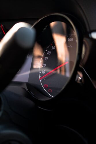 Close-up view of a car speedometer with light reflections on the dashboard.