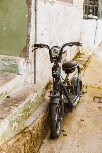 A classic-style Volta motor scooter parked on an aged, textured street, perfect for retro-themed advertising.