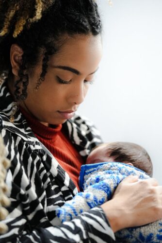 A tender moment of a mother bonding with her newborn child indoors.