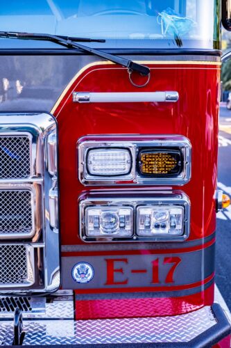 Vertical image of a red fire truck front with E-17 marking, showcasing details of lights and grill.
