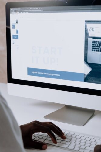 Person working on a website design for first-time entrepreneurs on a desktop computer.